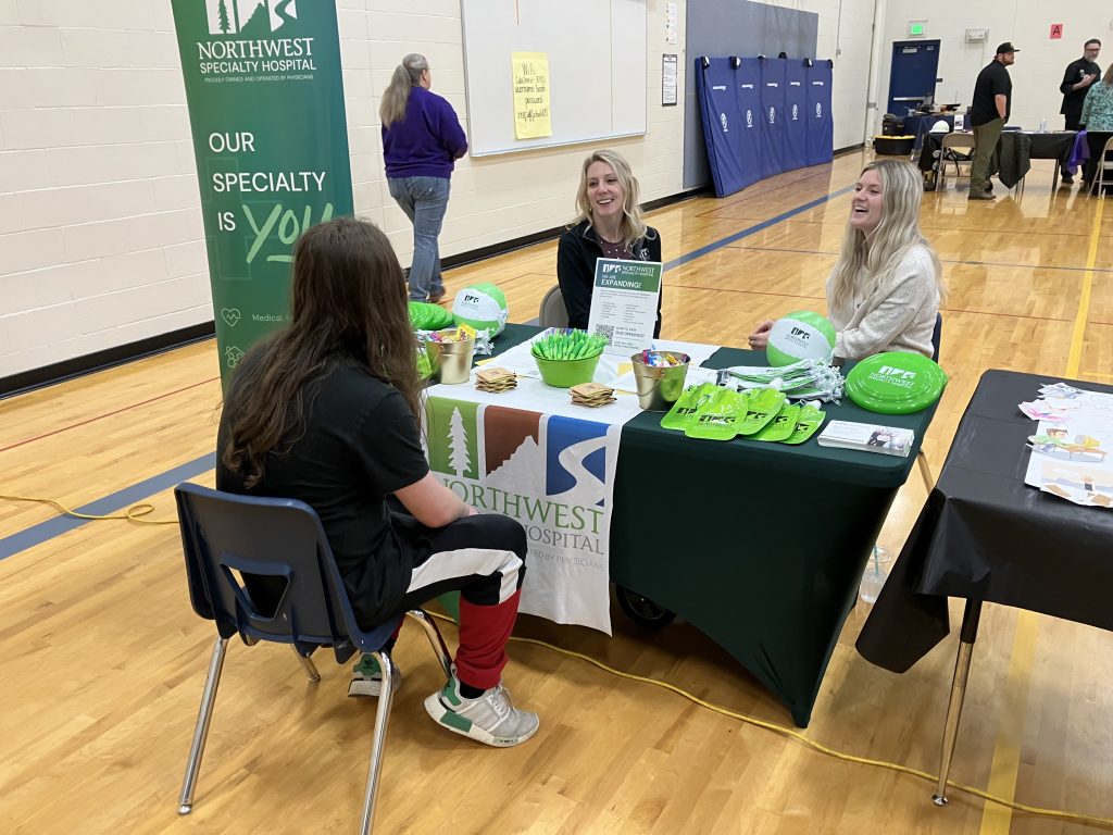 Northwest Specialty Hospital employees sitting at a career booth speaking with a student