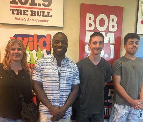 Three students standing with radio host Twitty.