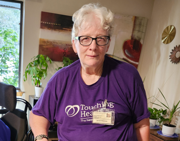 Jeanette wearing a purple Touching Hearts and Home tshirt