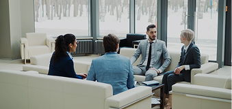 Business personel sitting on couches in suits talking