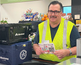 Raymond in high visibility yellow safety vest at an Alberstsons checkout counter holding coupons